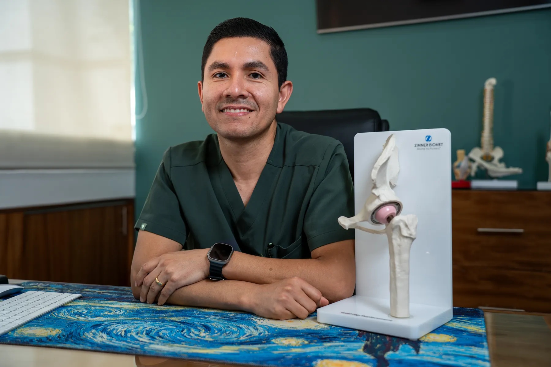 Dr. Galvis sonriendo en su consultorio junto a un modelo de cadera